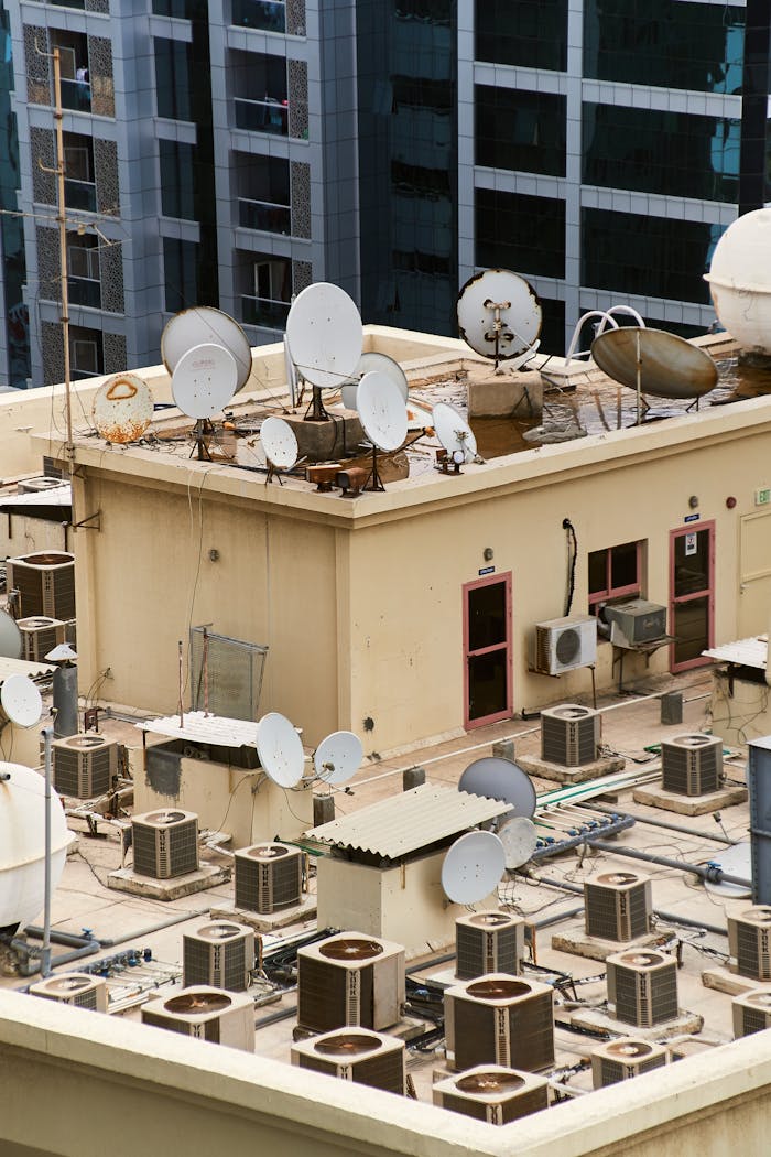 team-03 A rooftop view of satellite dishes and HVAC units on an urban building.